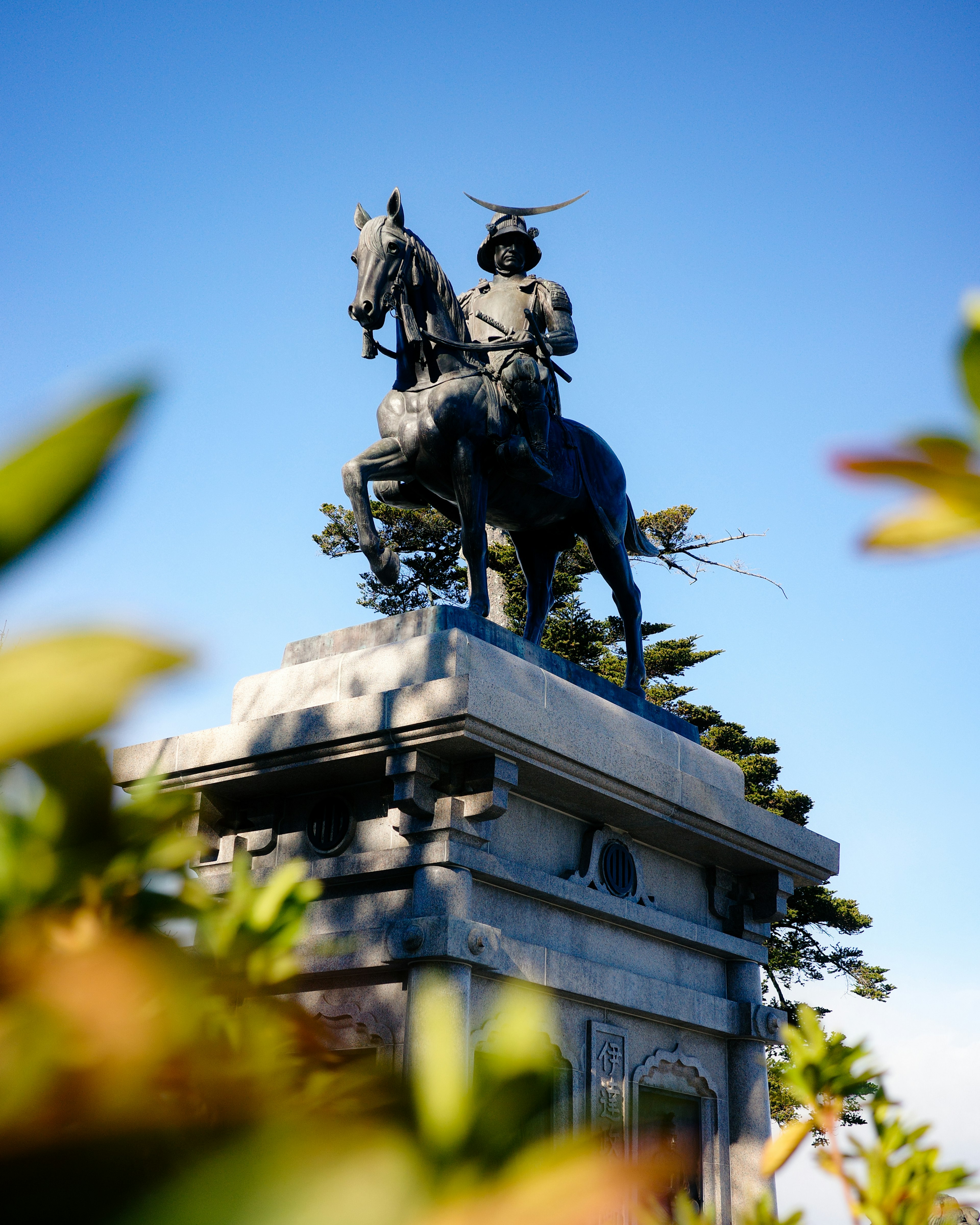 馬に乗った武士の銅像と青い空の背景