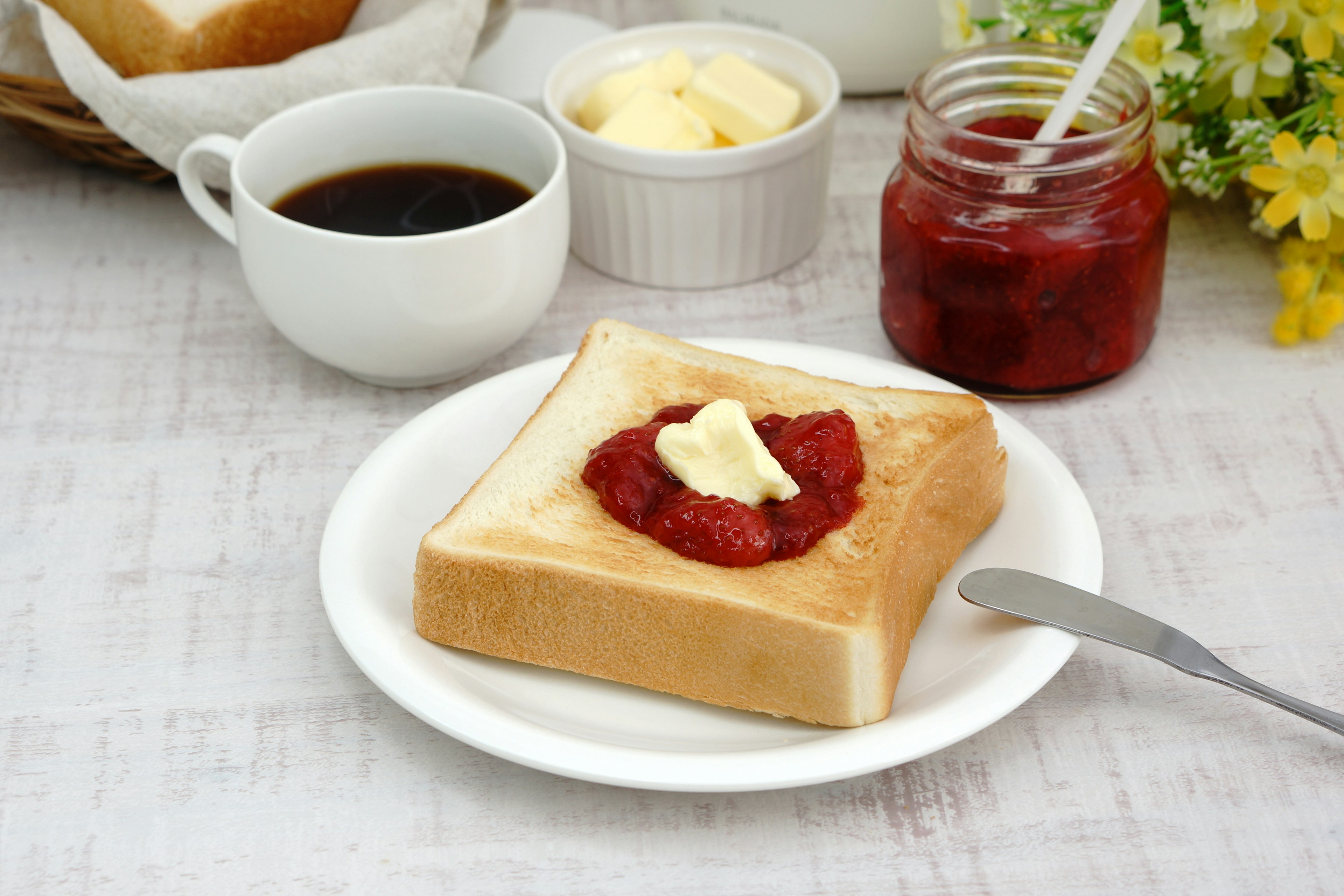 Scène de petit déjeuner avec du pain grillé avec du beurre et de la confiture café et crème au beurre en arrière-plan