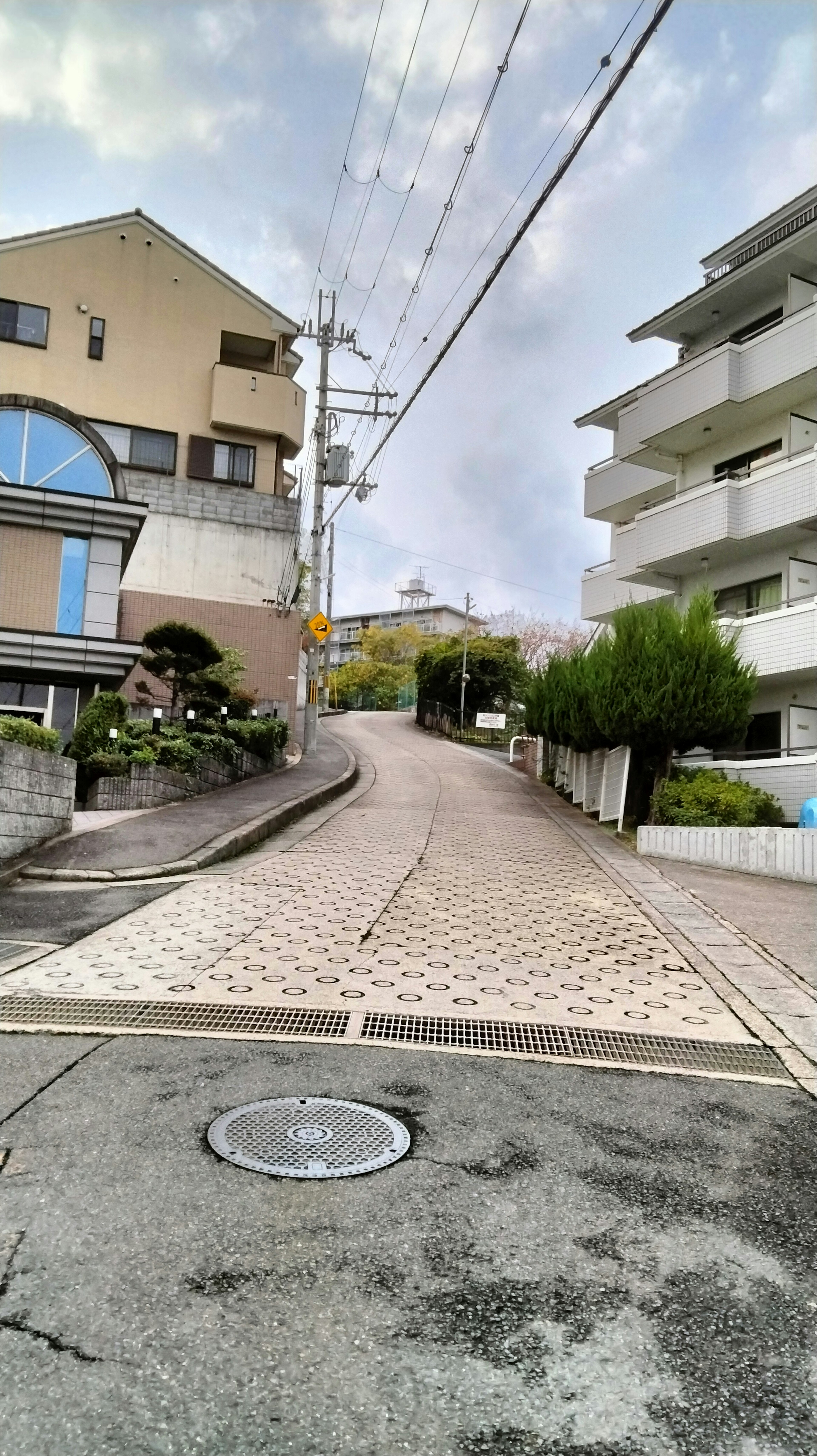 A sloped street in a residential area with surrounding buildings