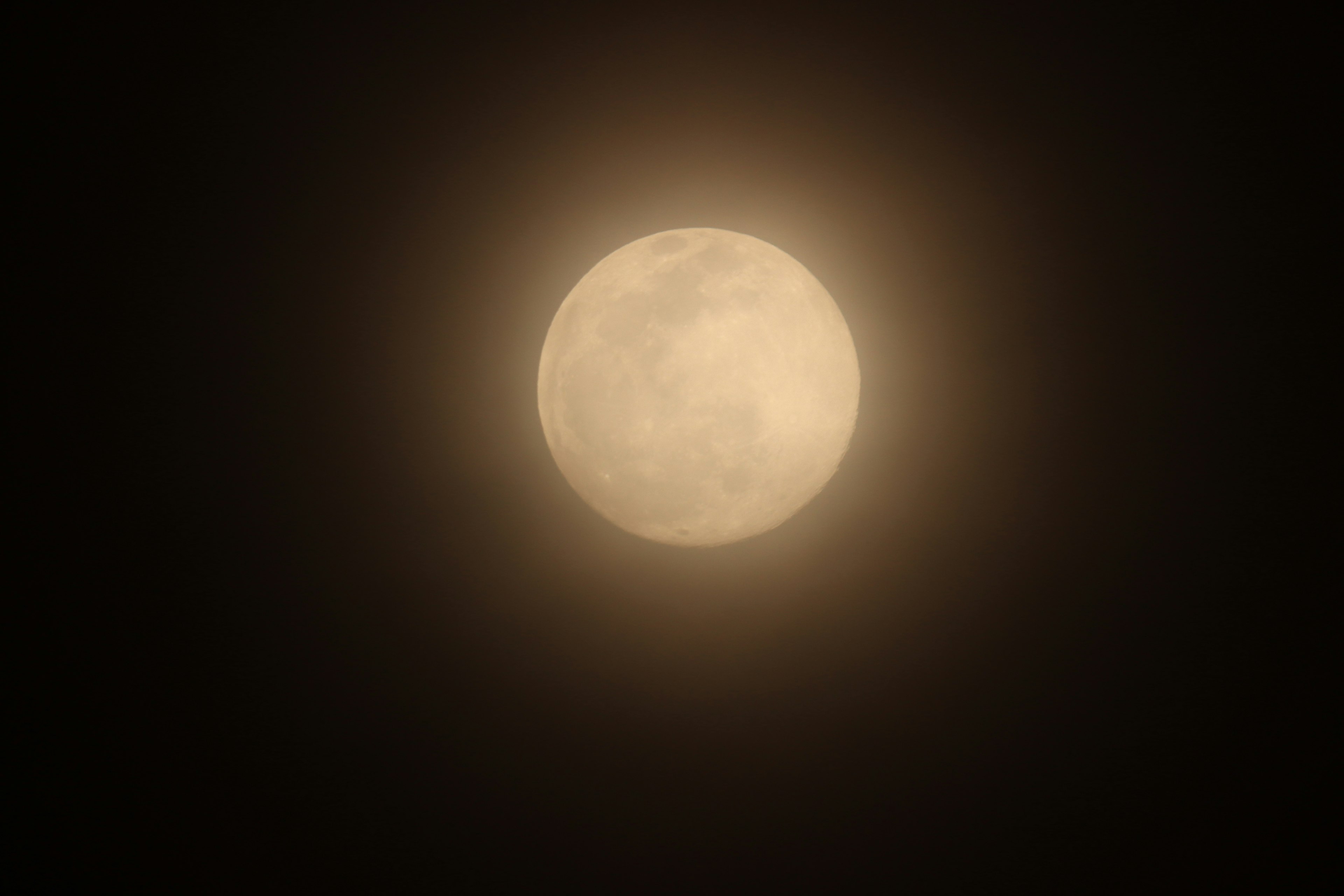 Bright full moon surrounded by thin clouds in the night sky