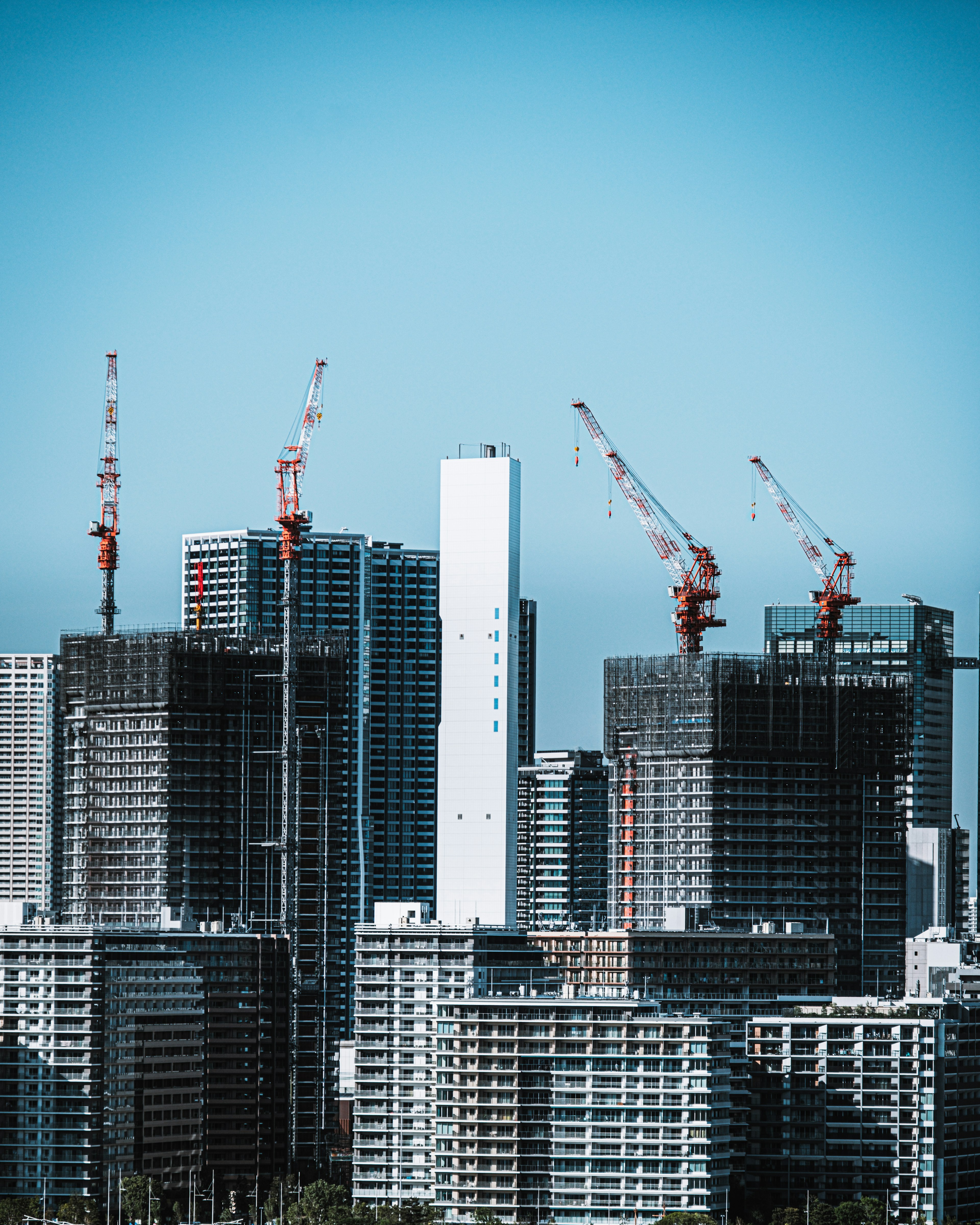 Construction site of skyscrapers with cranes under a clear blue sky