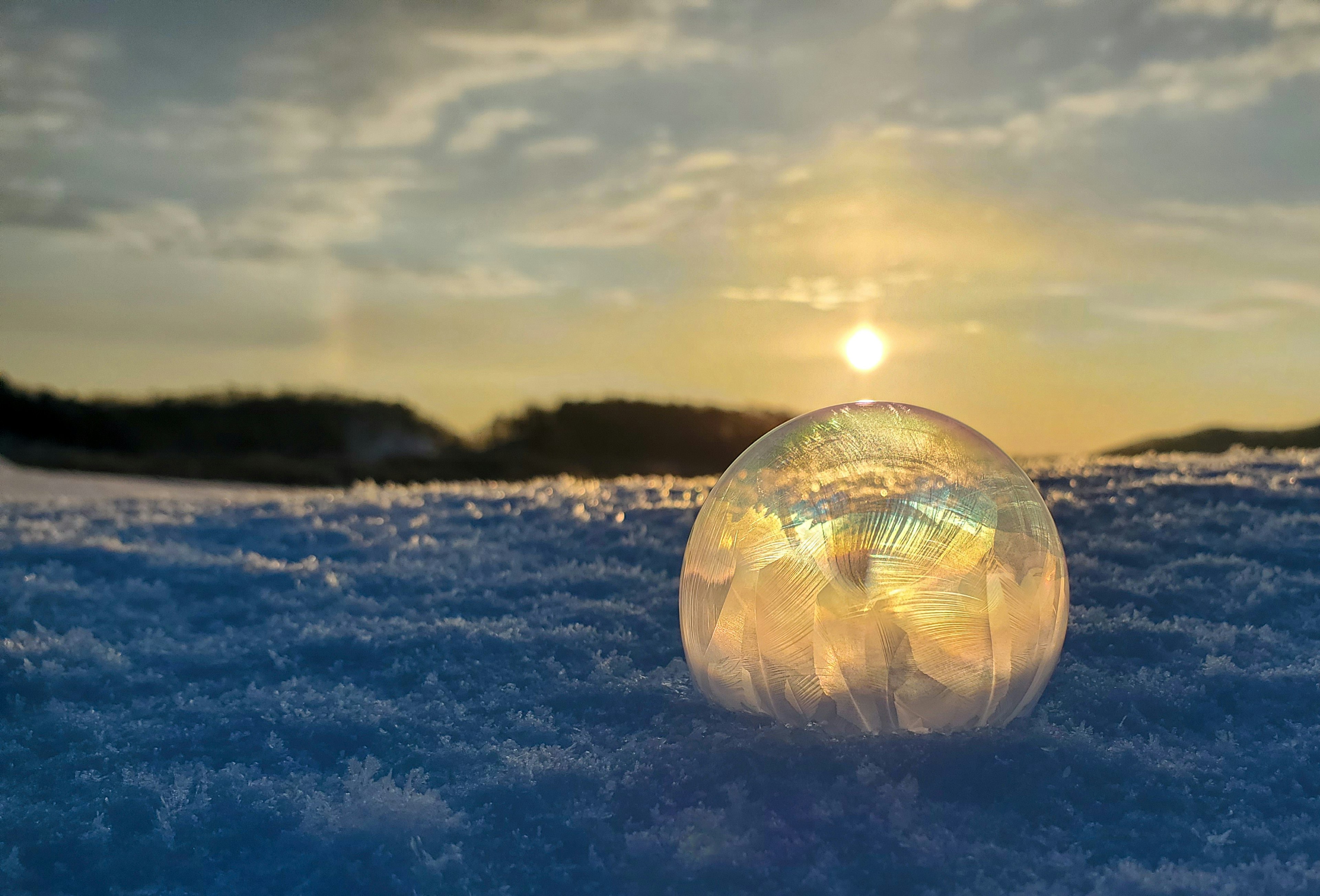 Una scena bella di una bolla di ghiaccio sulla neve che riflette il tramonto