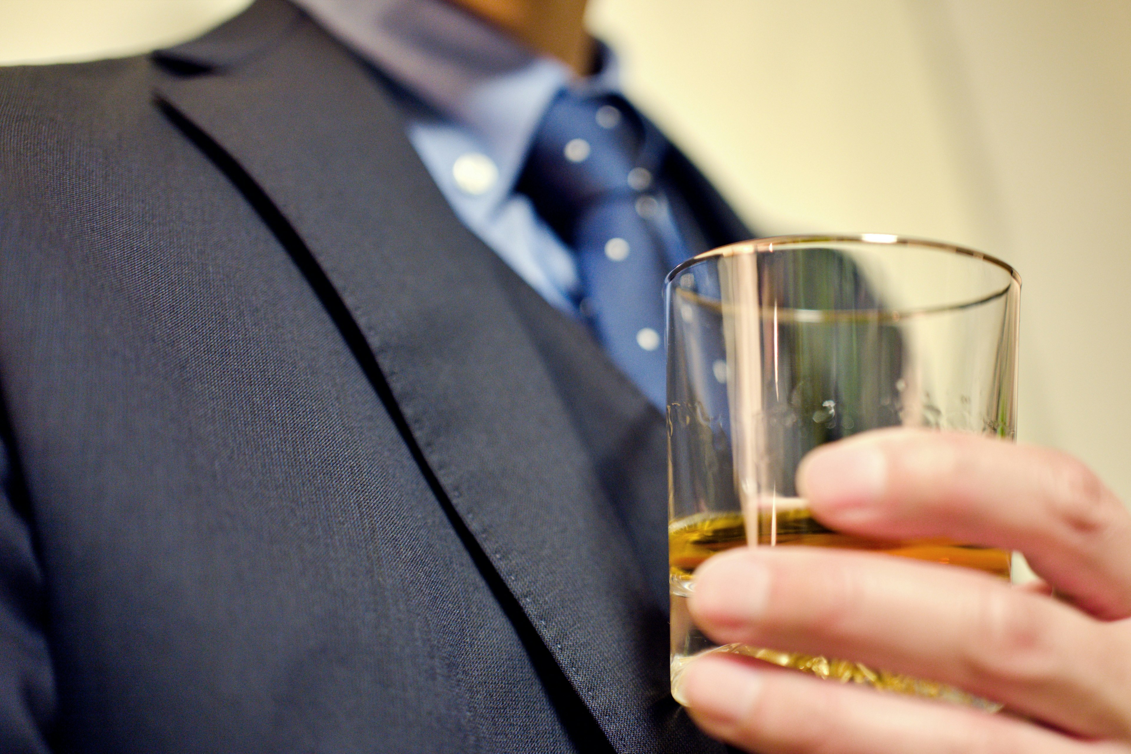 Un homme en costume tenant un verre de whisky