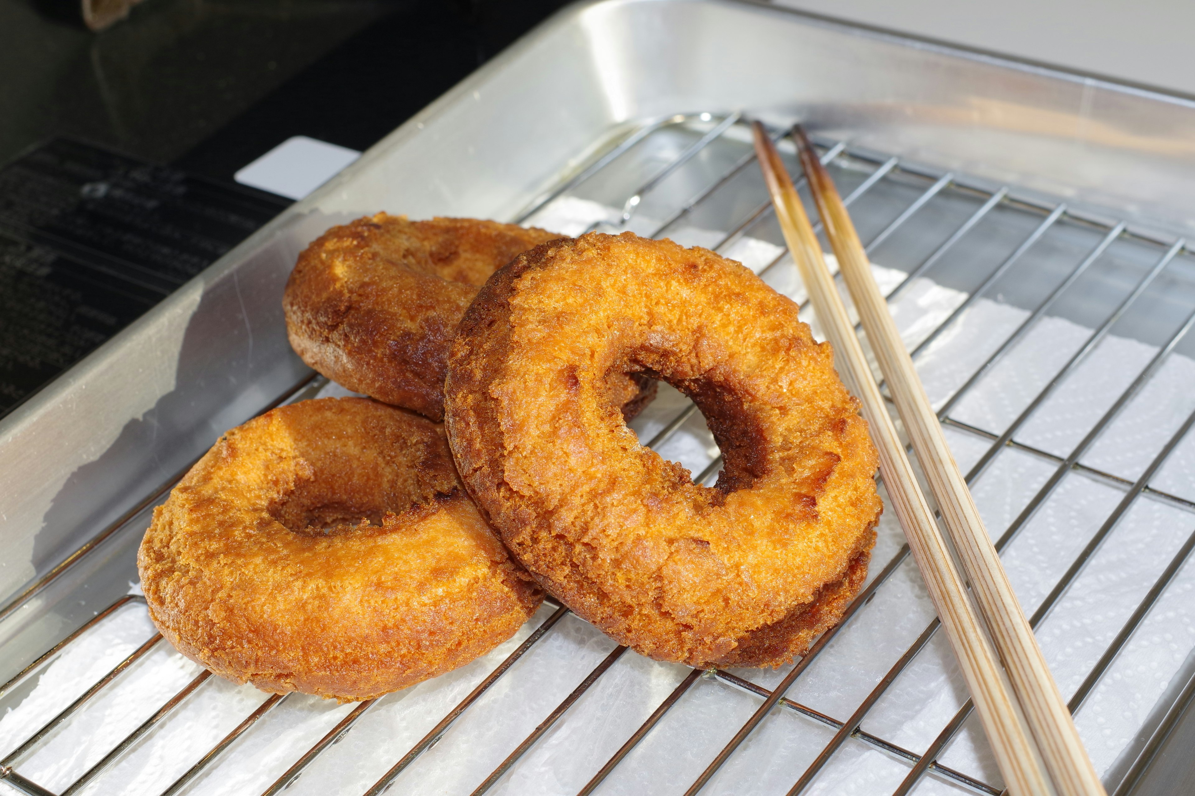 Donat goreng berwarna emas dengan bagian luar renyah diletakkan di atas nampan