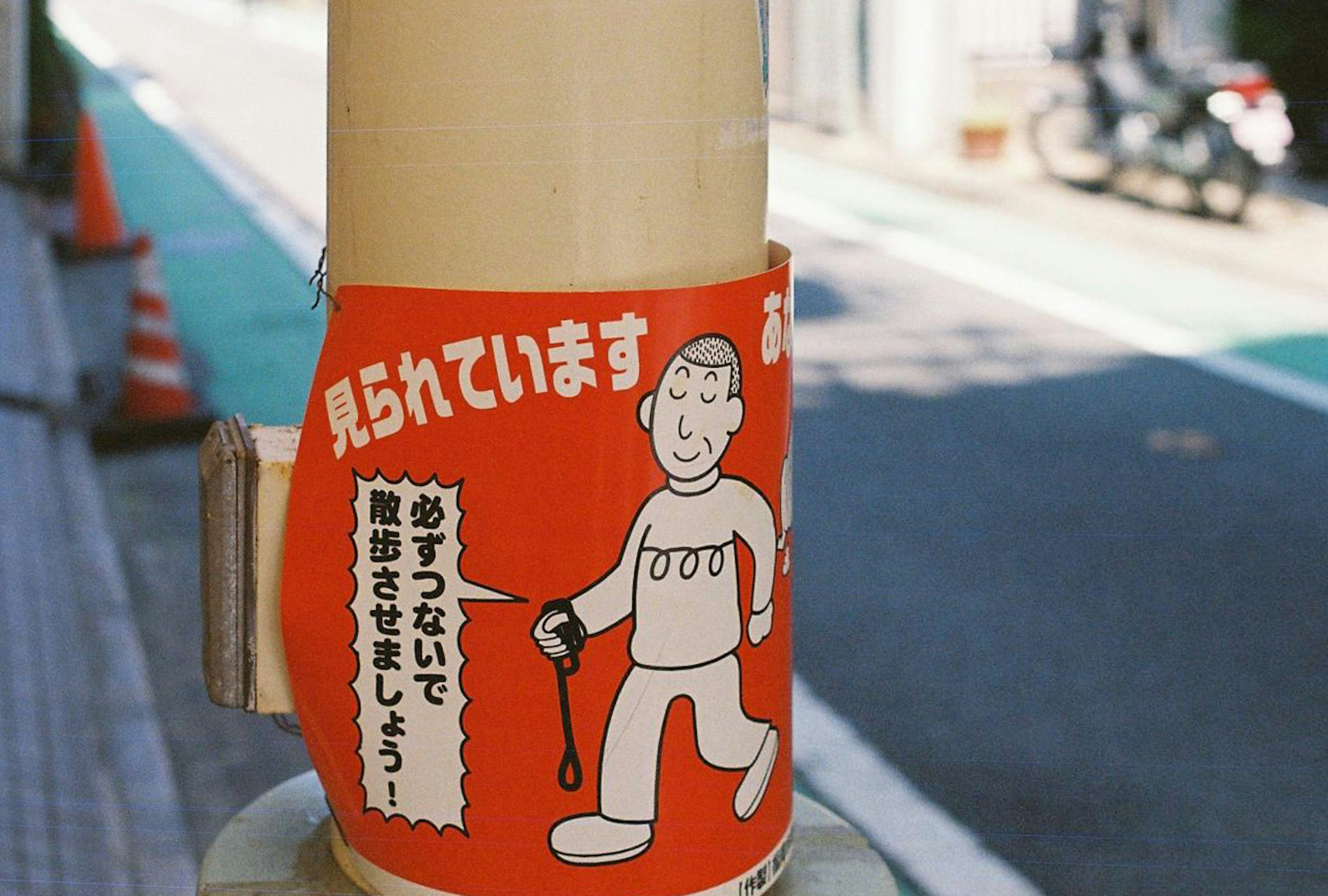 Image of a pole with a warning sign featuring a pedestrian illustration on a red background