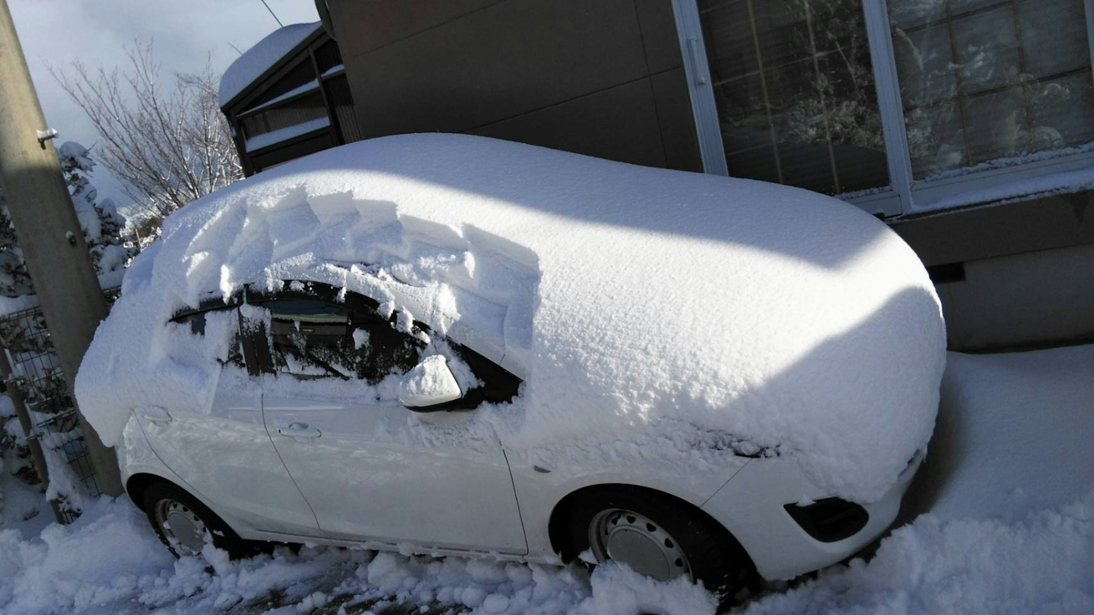 Coche cubierto de nieve espesa con un paisaje nevado alrededor