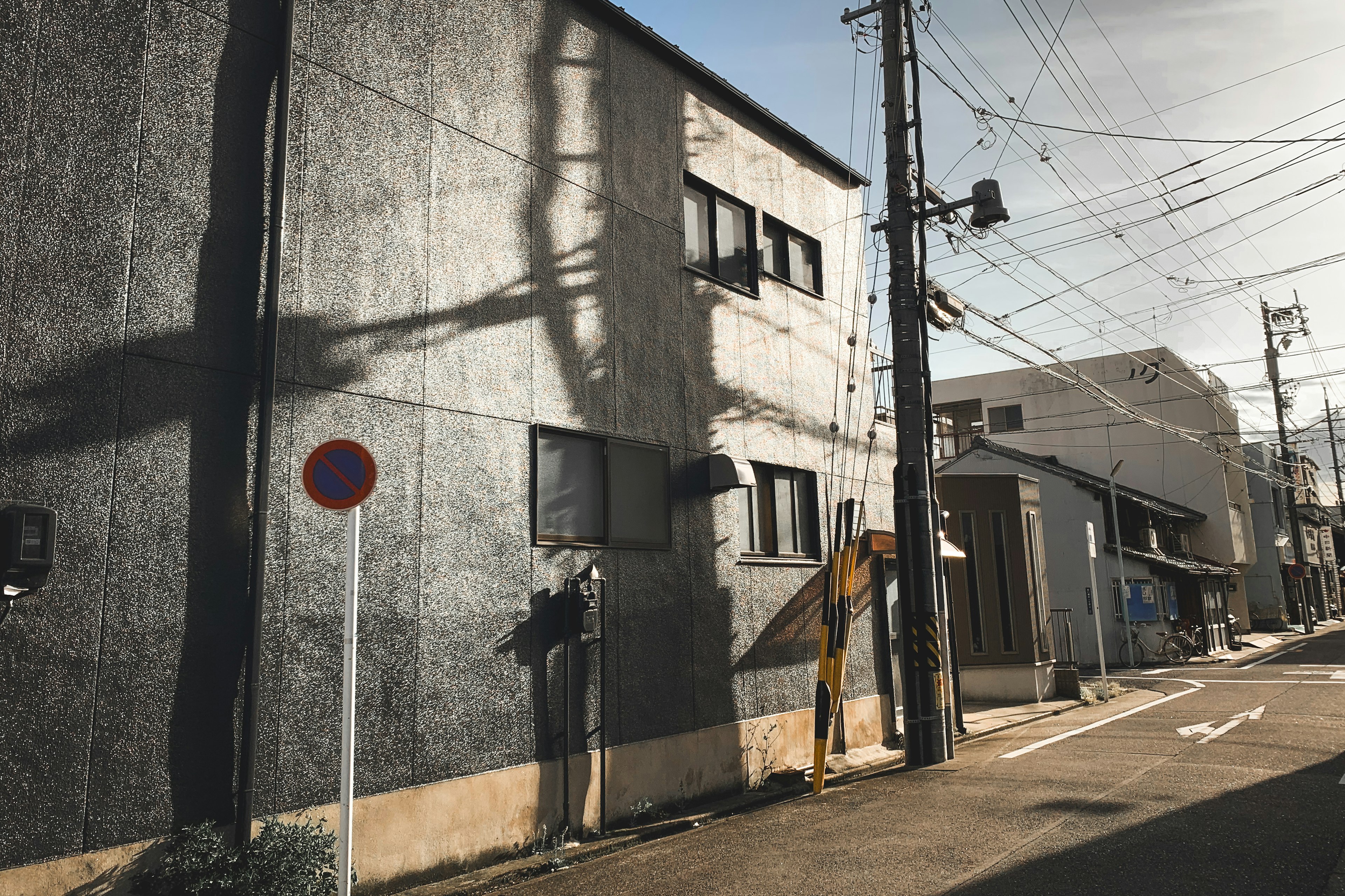 Graues Gebäude in einer engen Gasse mit kontrastierenden Schatten