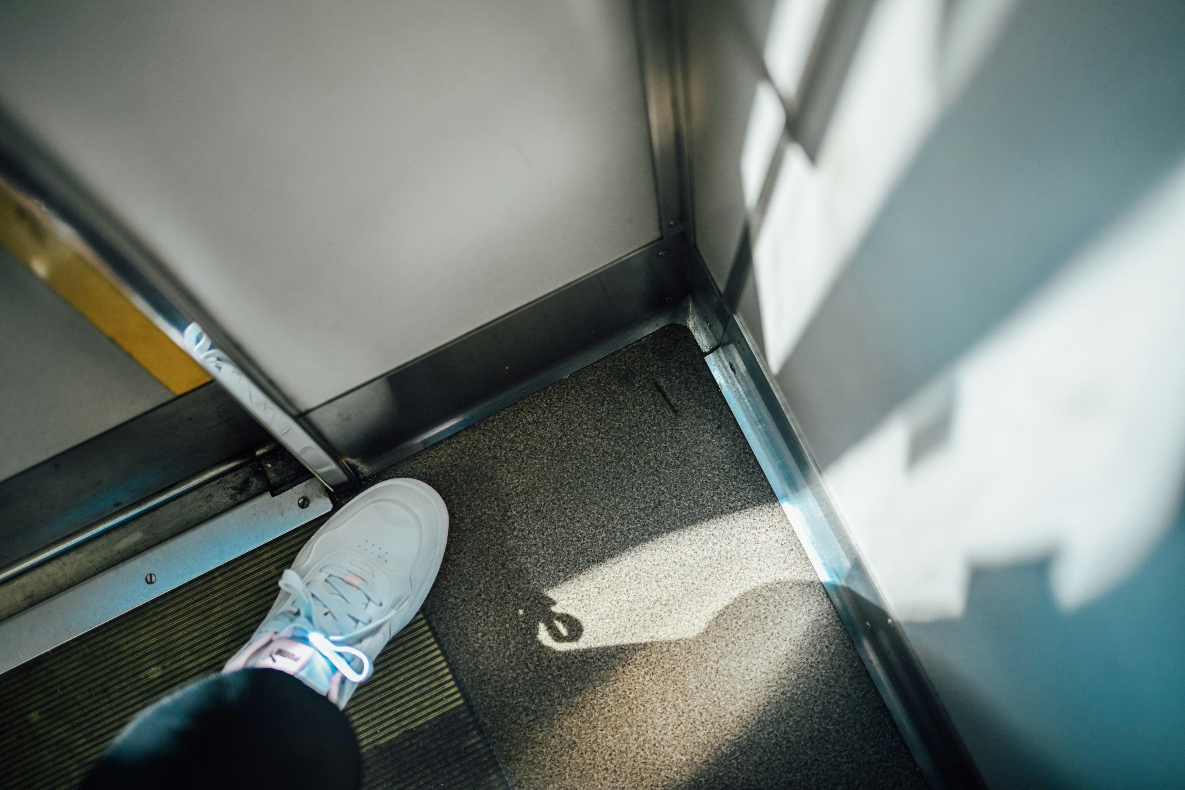 Pie dentro de un ascensor proyectando una sombra en el suelo