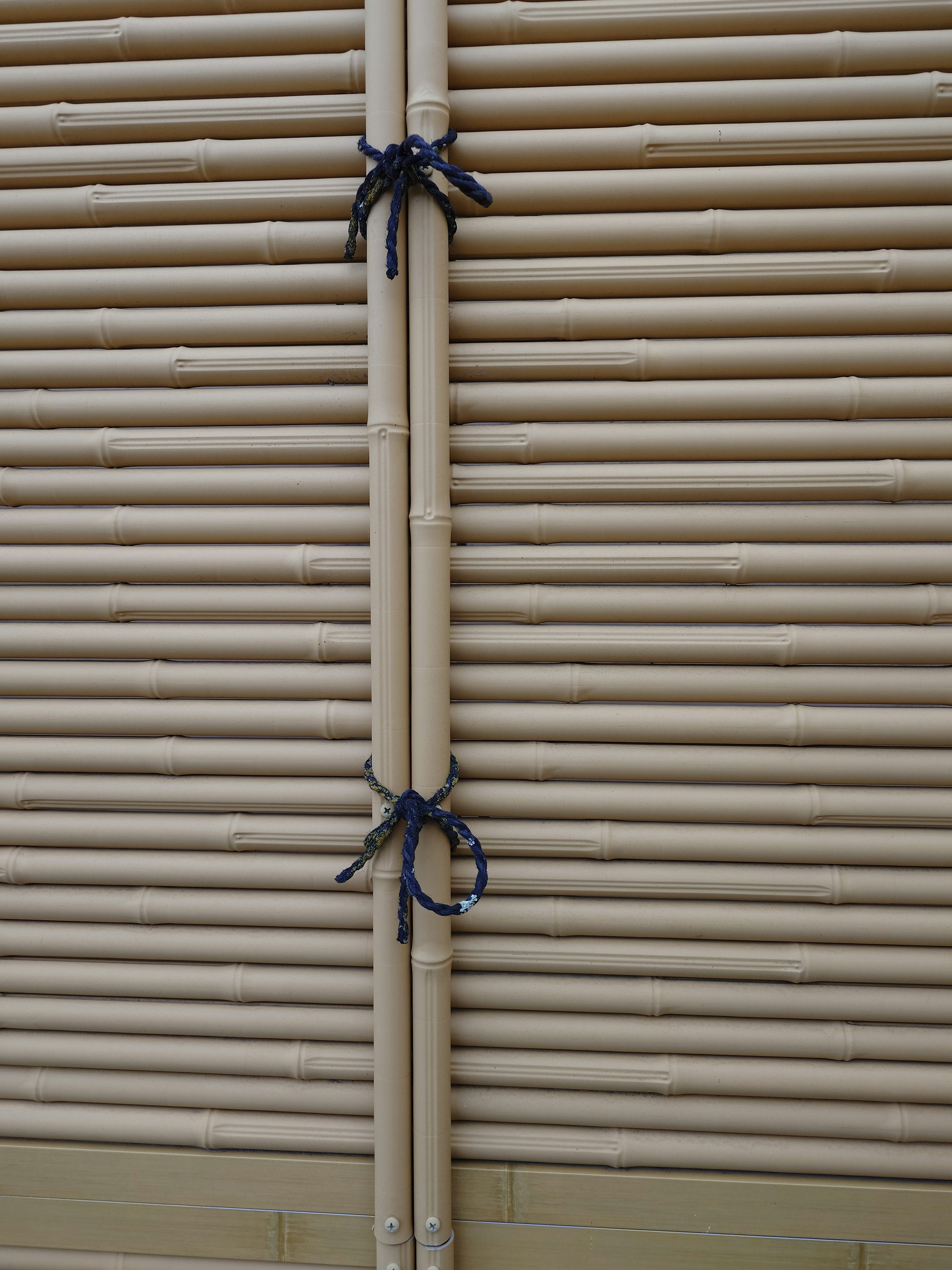 Image of bamboo blinds arranged with distinctive black ribbons tying them