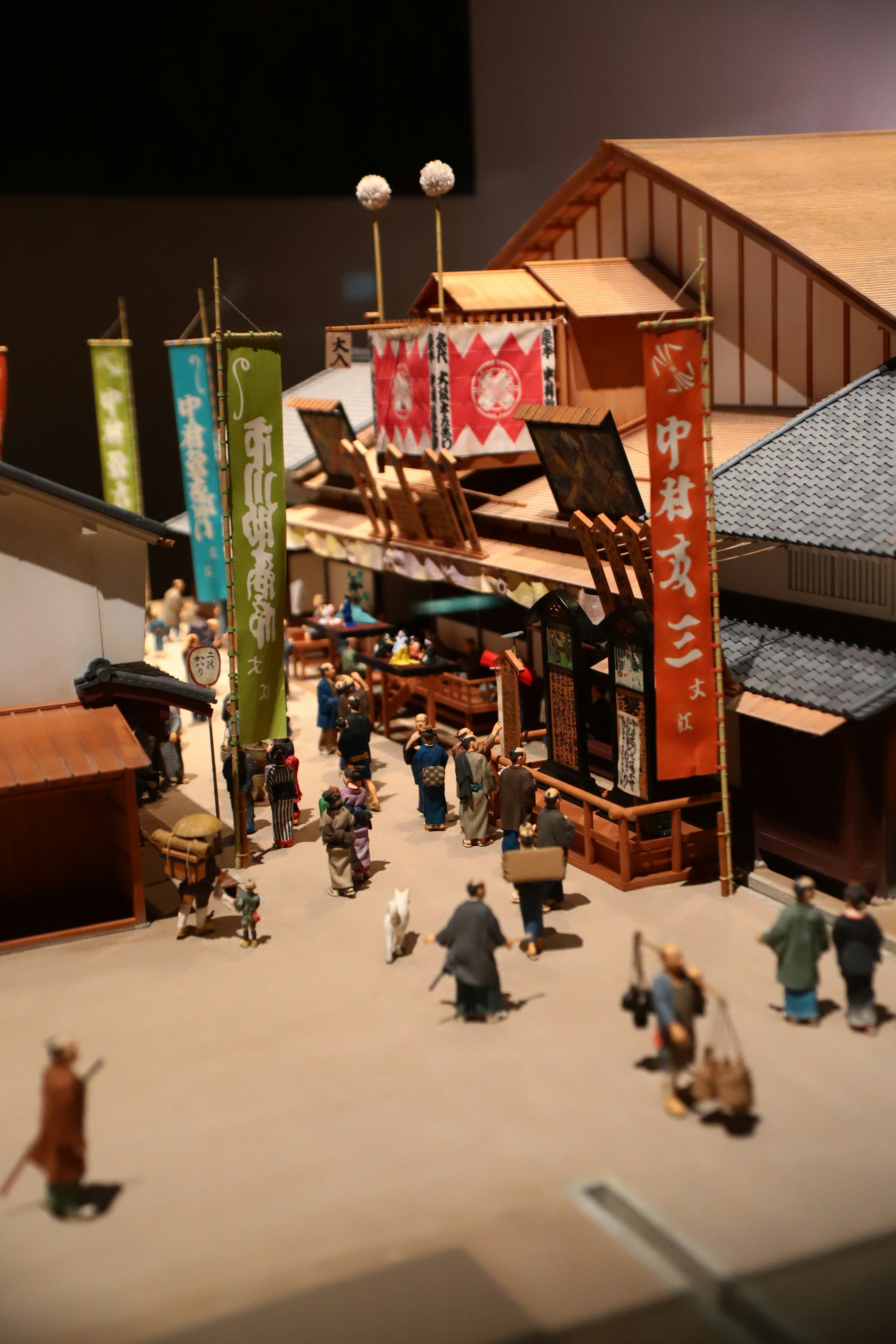 Detailed miniature street scene with people walking and colorful banners