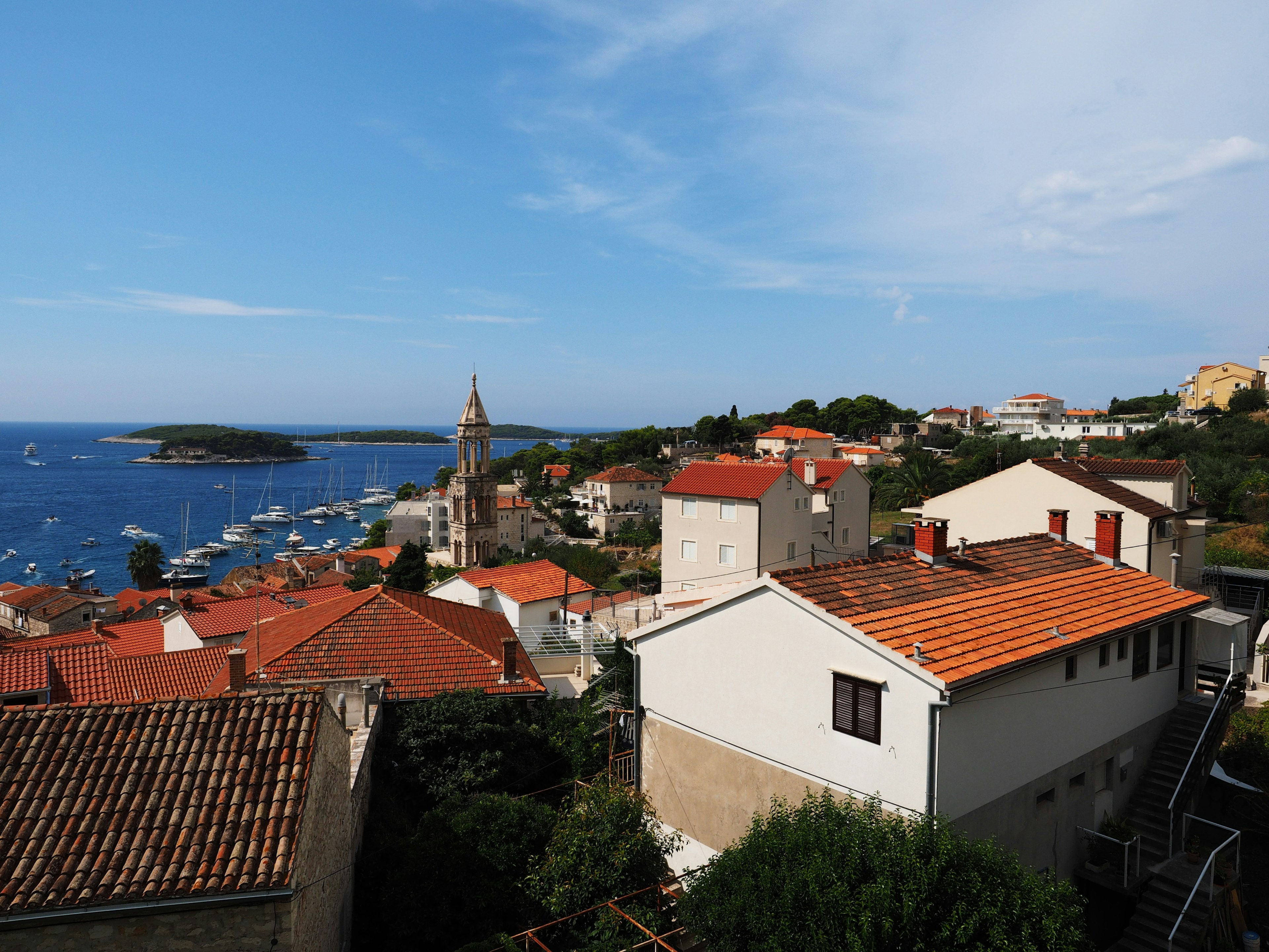 A view of houses with red roofs against a blue sea and a small harbor