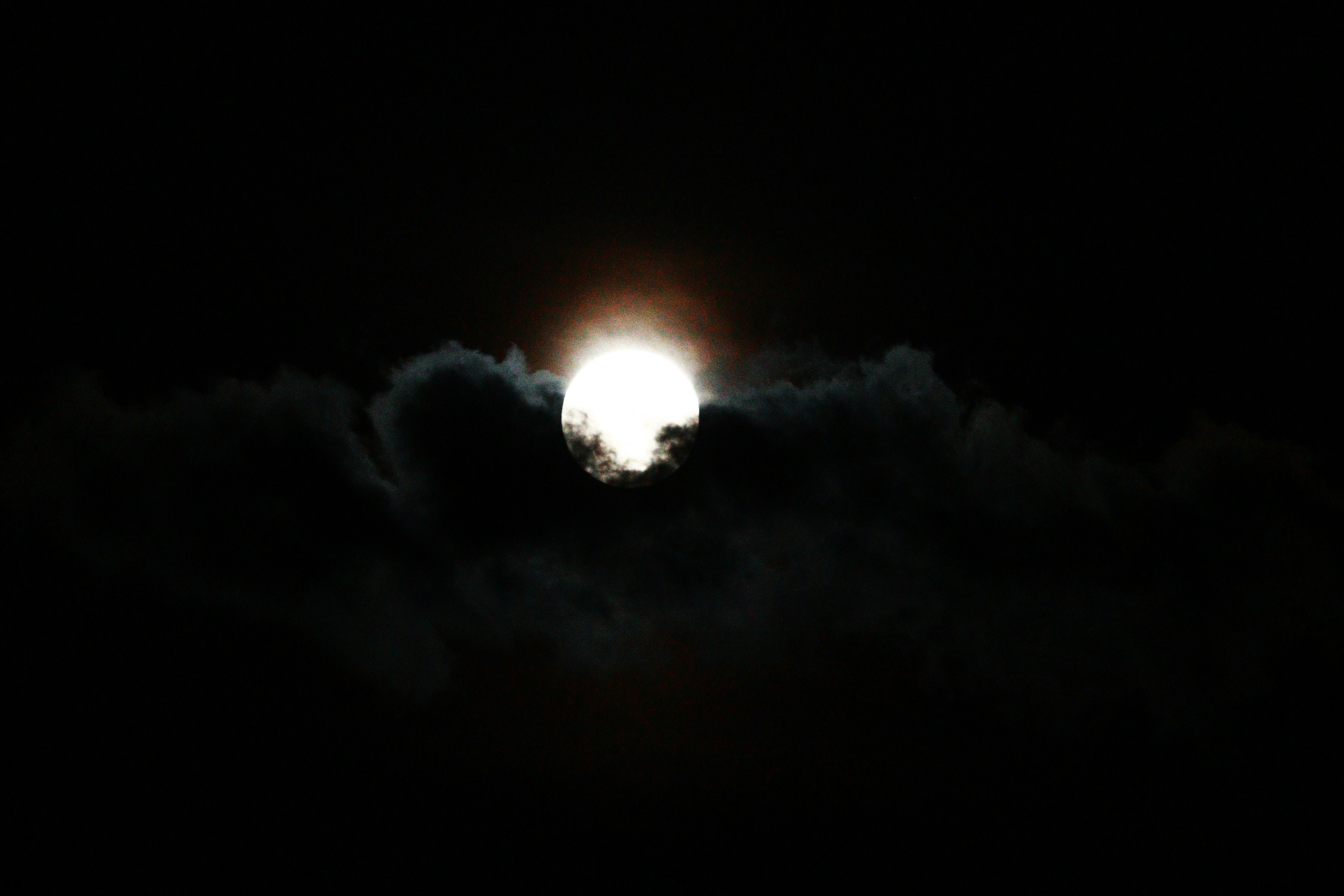 Una luna brillante parzialmente nascosta da nuvole scure in un cielo notturno