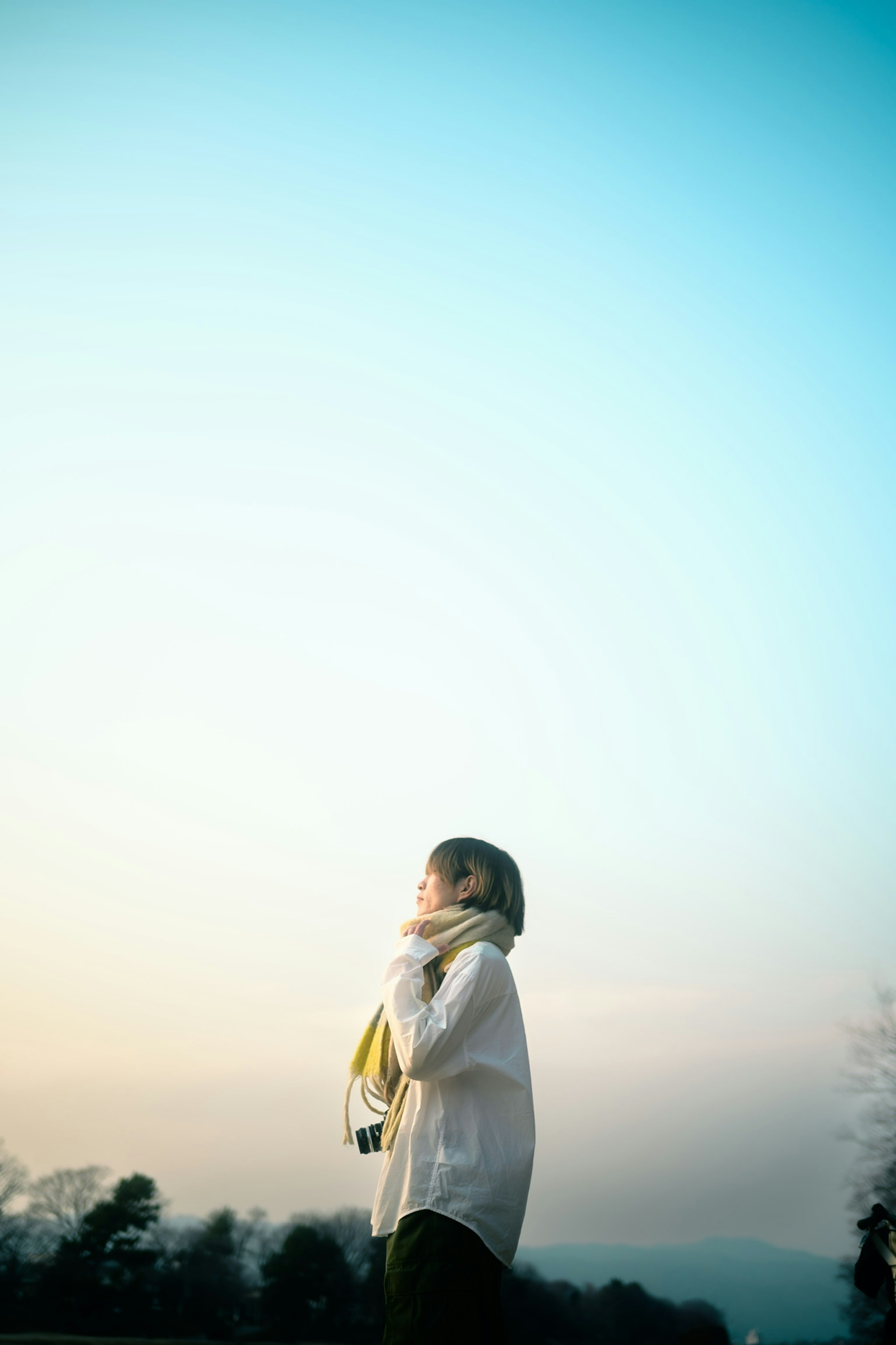 女性がスカーフを巻いて空を見上げるシルエット