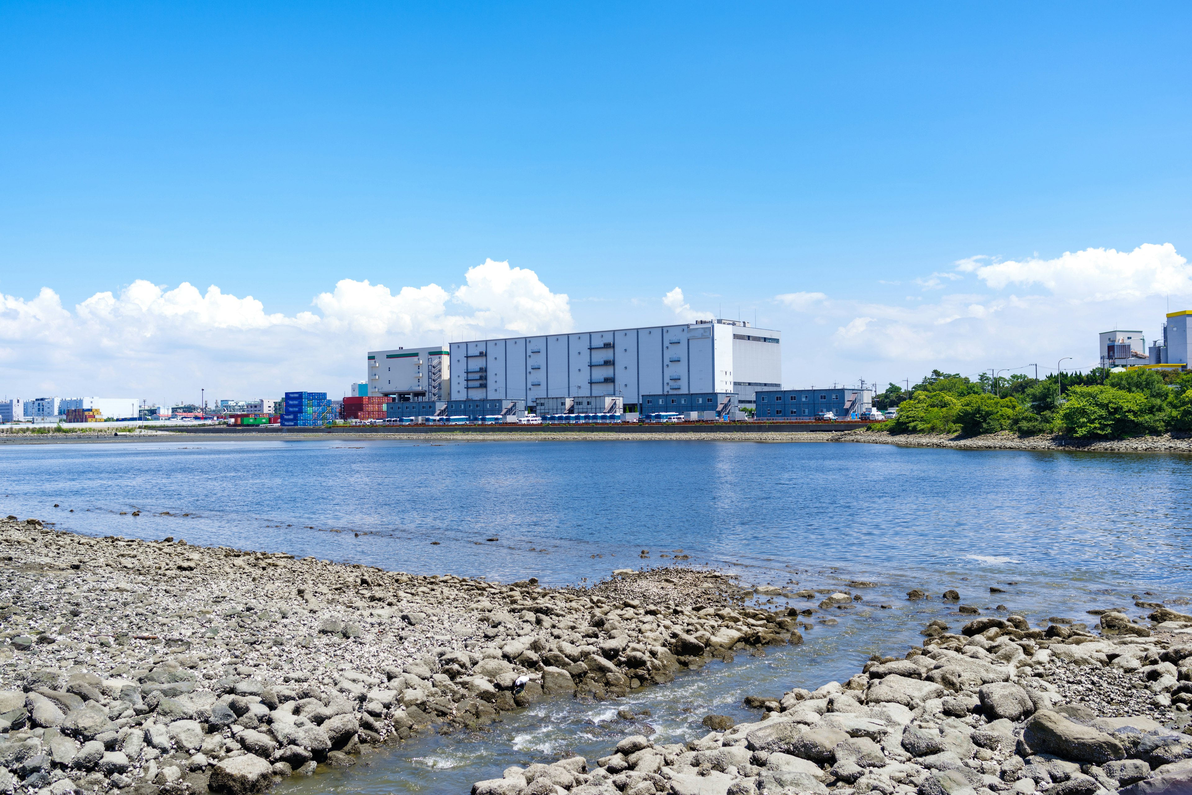 Riverbank view with modern buildings under a clear blue sky