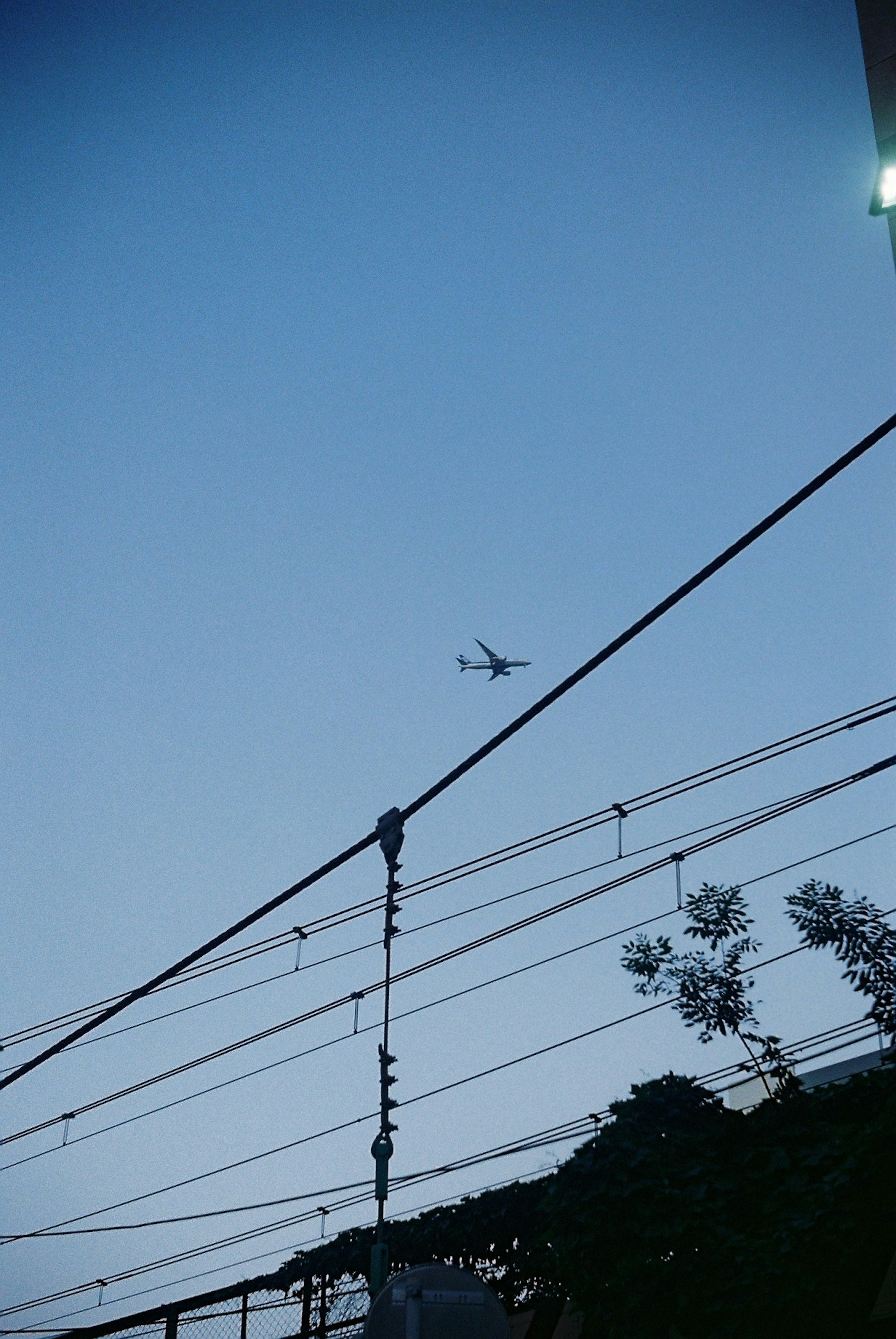 青空に飛行機が飛んでいる写真 電線が画面を横切る