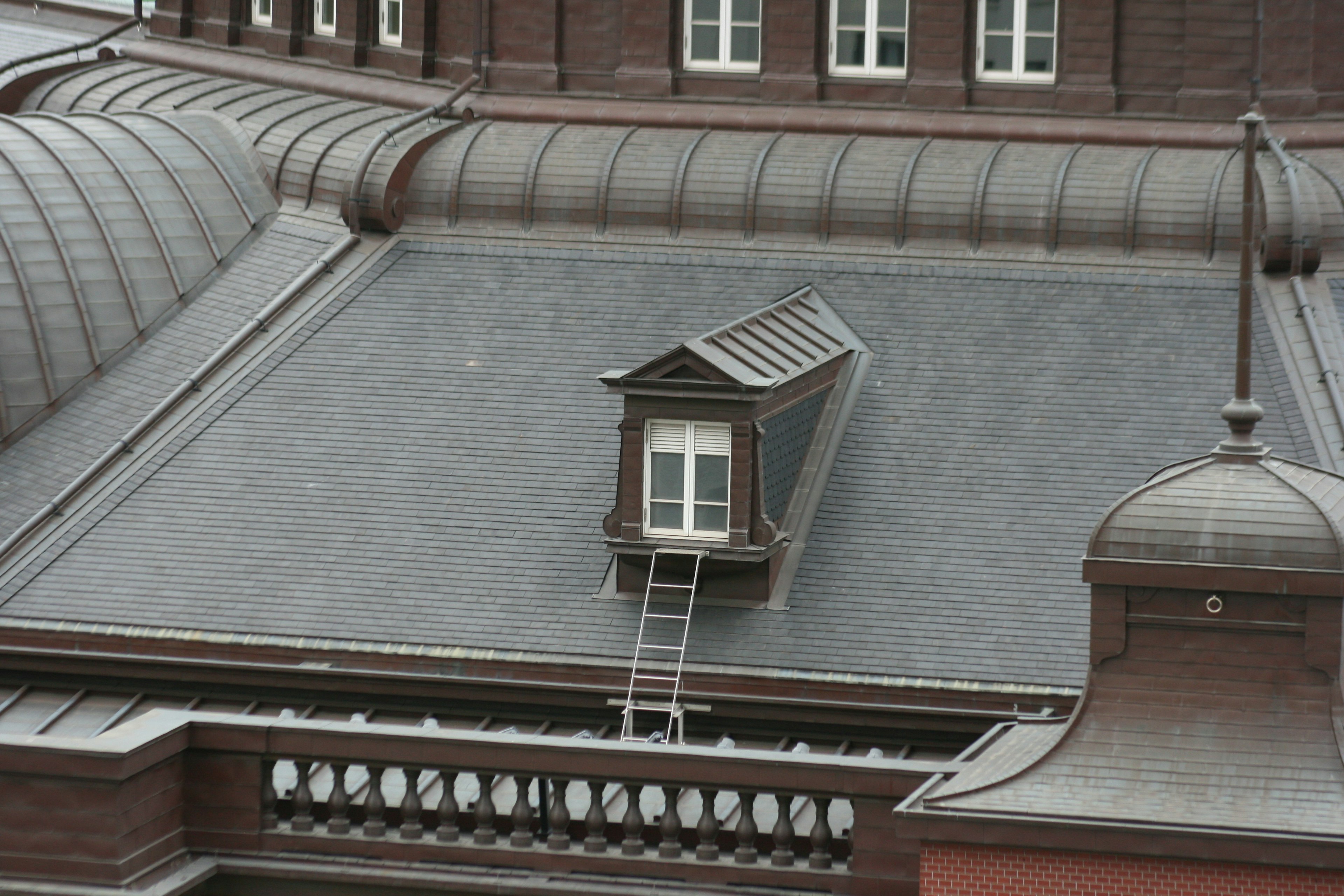 Gros plan sur un toit de bâtiment avec une petite fenêtre et une échelle