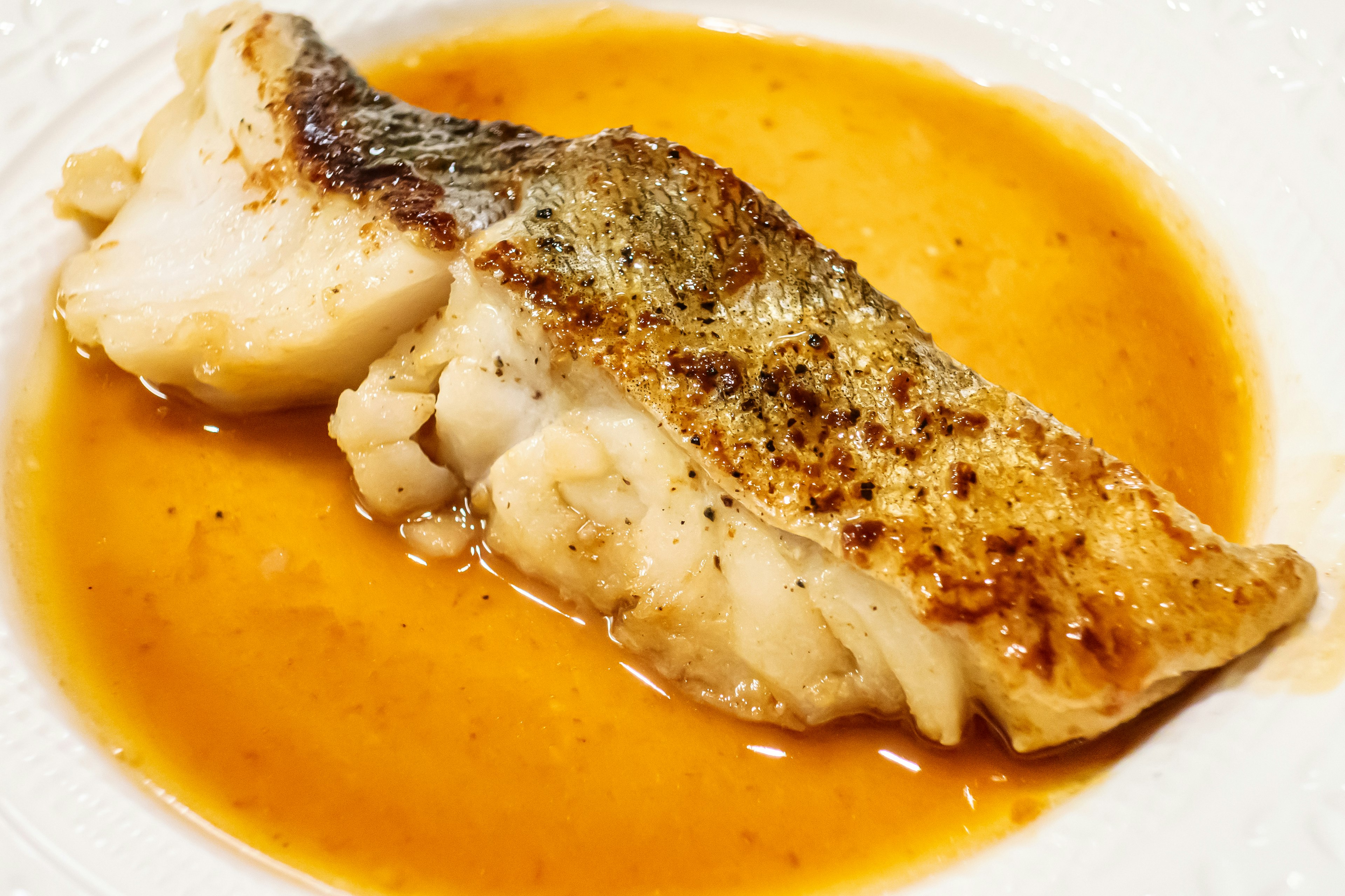 Seared white fish fillet in orange sauce