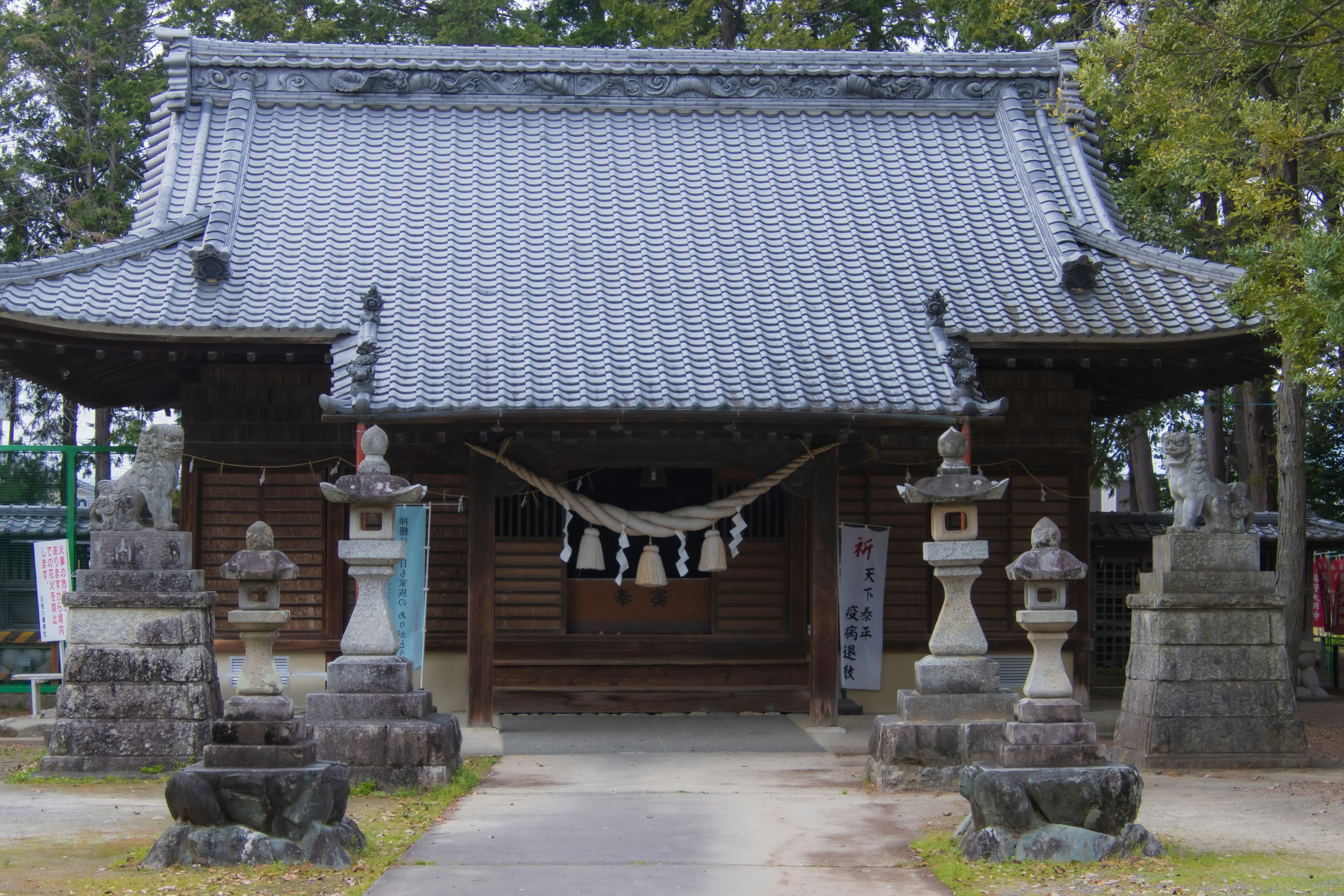 Eingang zu einem traditionellen japanischen Schrein mit einem Holzgebäude und Steinstatuen