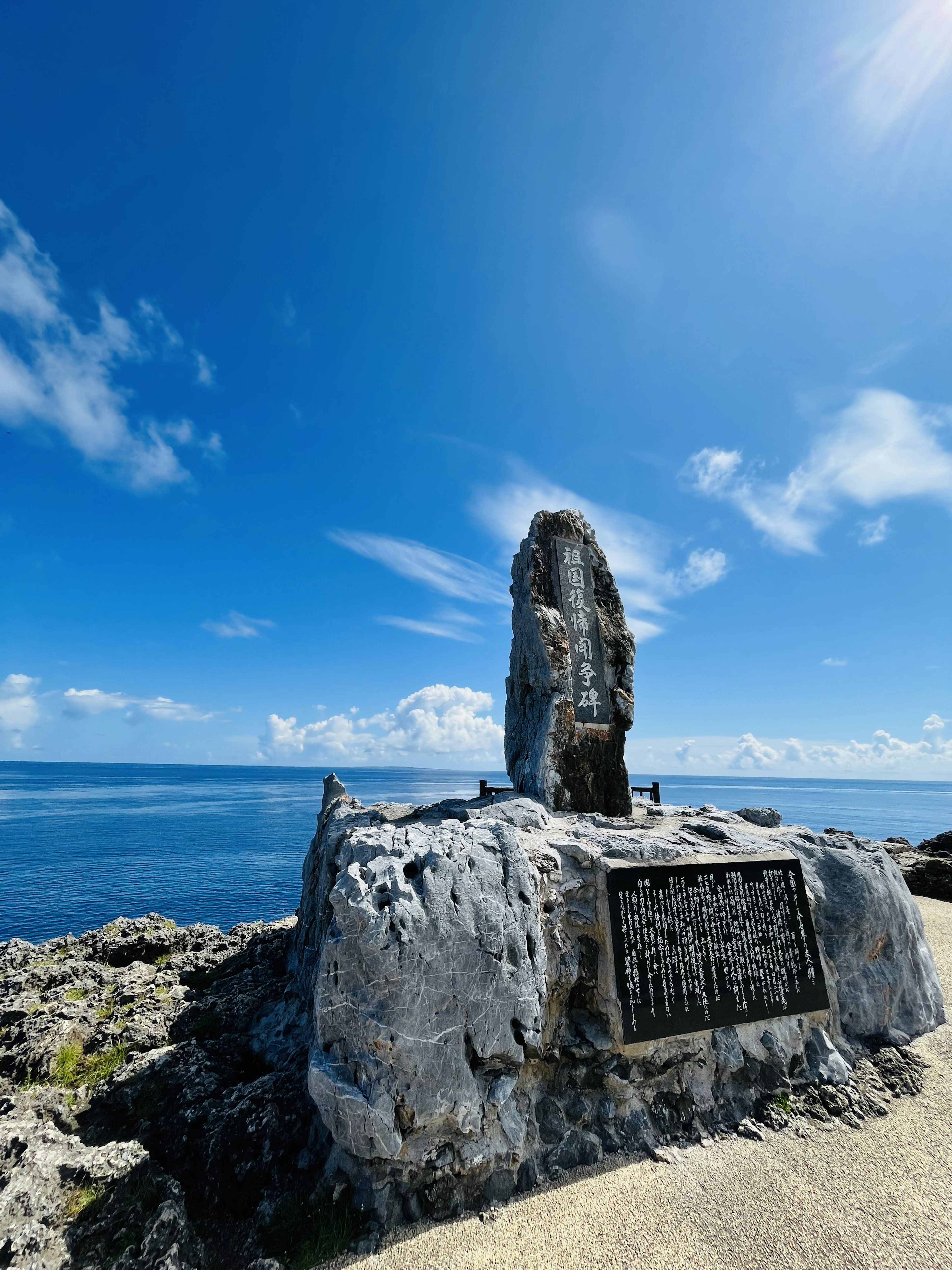 青い空と海の背景に立つ記念碑の石